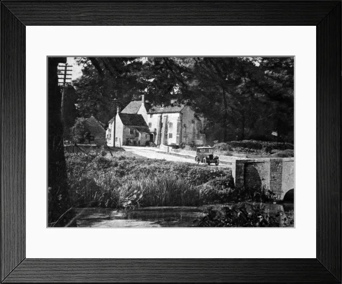 Framed Print : Morris Minor driving through English village
