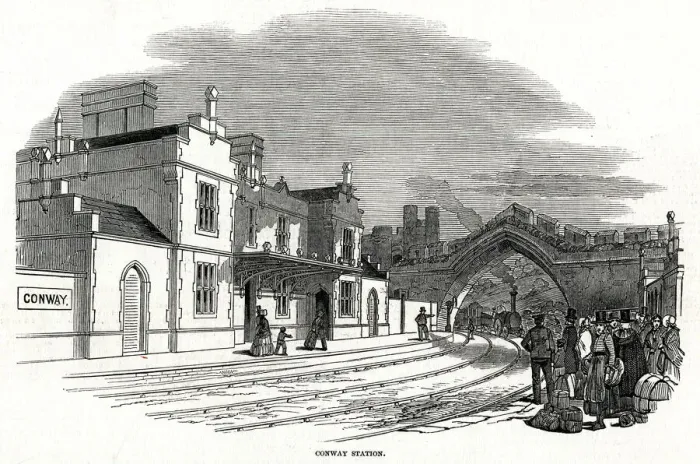 Framed Print : Train passing under arch into Conway railway station 1848