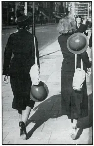 Girl Prints: Backs of two walking girls holding helmets, September 1939