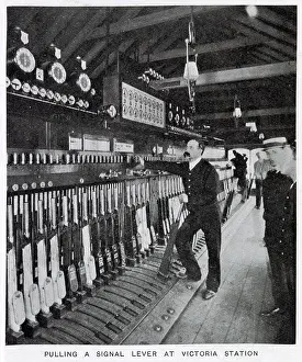 1907 Prints: Photograph showing the signalman in the act of pulling a signal lever to allow a train to enter one of the platforms